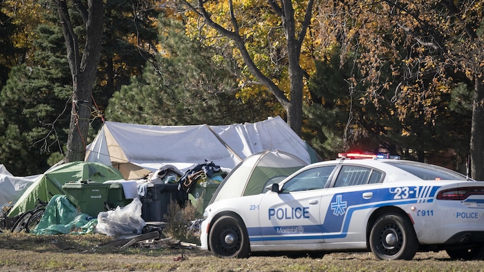 Une voiture de police dans un campement de personnes itinérantes.