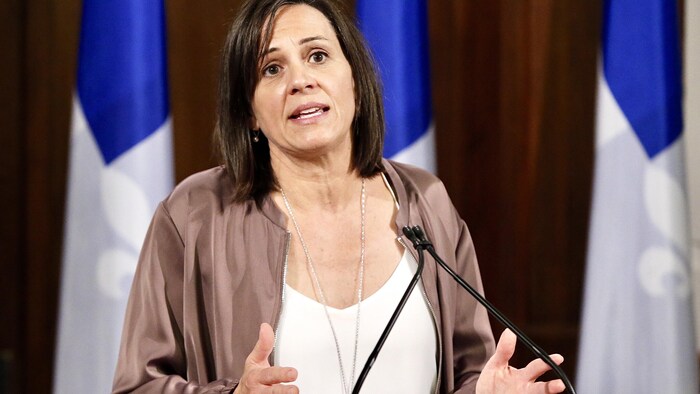 Isabelle Charest en conférence de presse devant des drapeaux du Québec