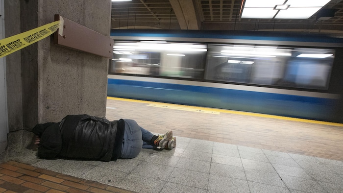 Une personne couchée sur un banc de briques, recroquevillée, à la station de métro Bonaventure.
