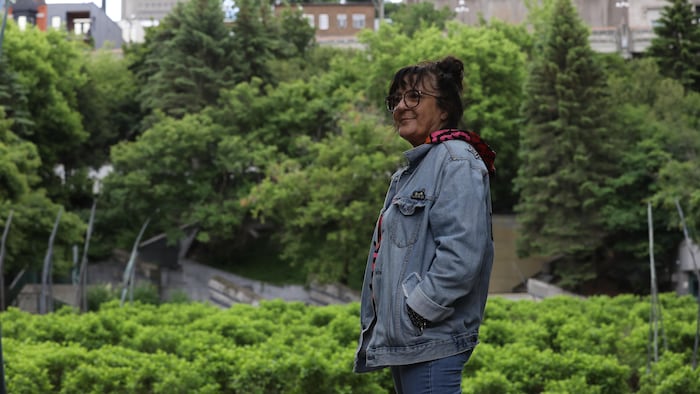 Une femme pose devant un jardin public.