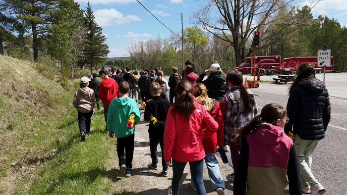 Un groupe de jeunes et d'adultes marchent sur le bord de la route. 