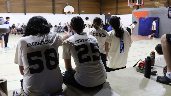 Des jeunes de dos regardant un match.