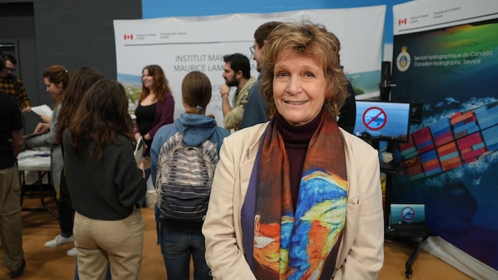 Sylvie Roy in front of a poster of the Ministry of Fisheries and Oceans.