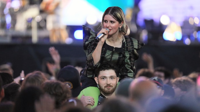 Une artiste dans la foule sur les épaules d'un agent de sécurité.