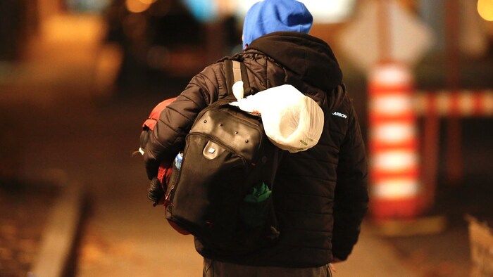 Un homme en situation d’itinérance photographié de dos, la nuit, au centre-ville de Québec.