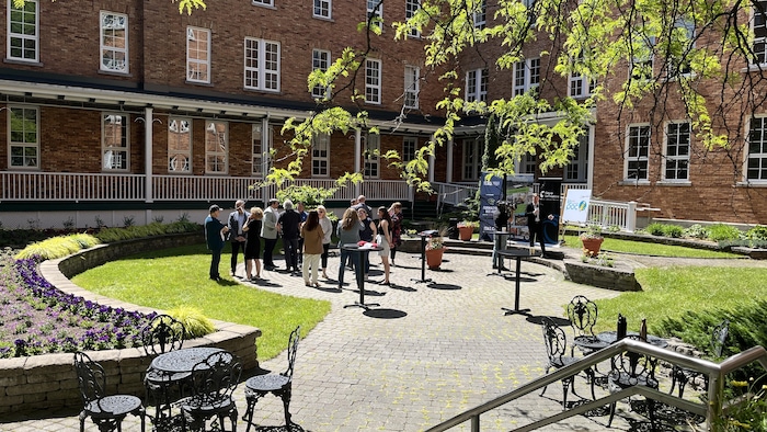 Un groupe de personnes réunies dans un jardin ensoleillé autour de tables dressées pour l'occasion.