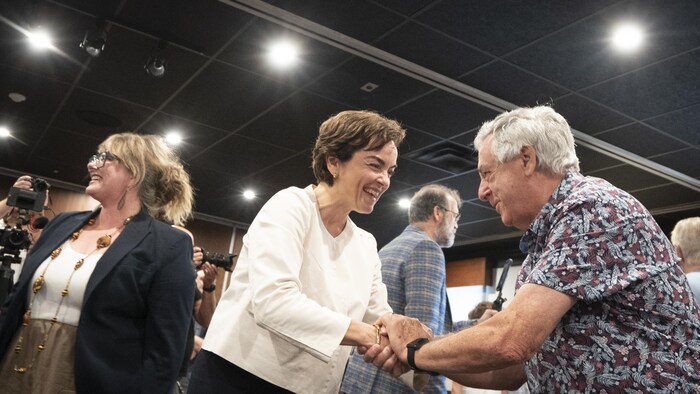 Christine Fréchette serrant la main d'un militant dans un rassemblement politique.
