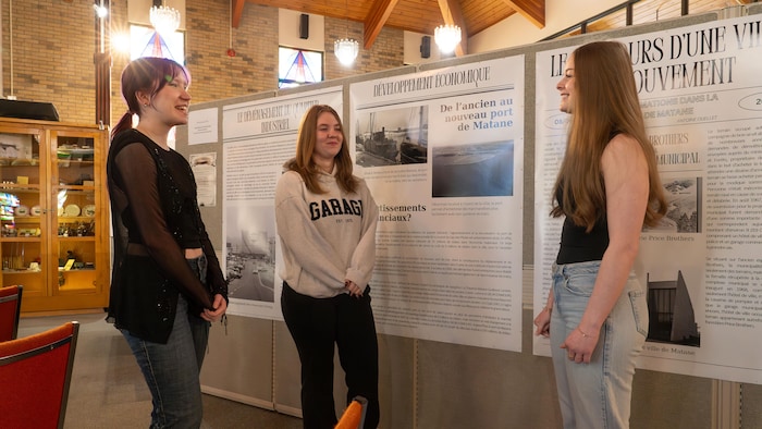 Trois filles devant un panneau d'exposition.
