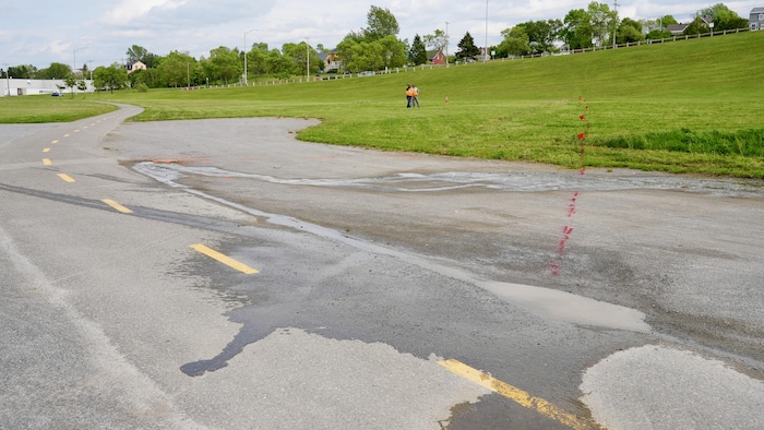 Deux hommes pointent l'horizon au site d'une fuite d'eau sur le réseau d'aqueduc. 