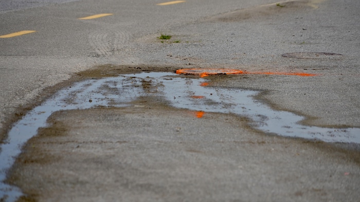 De l'eau coule sur de l'asphalte près d'une piste cyclable. 