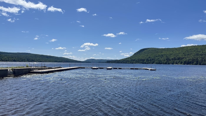 UN quai flottant sur l'eau d'un lac entouré de montagnes boisées.