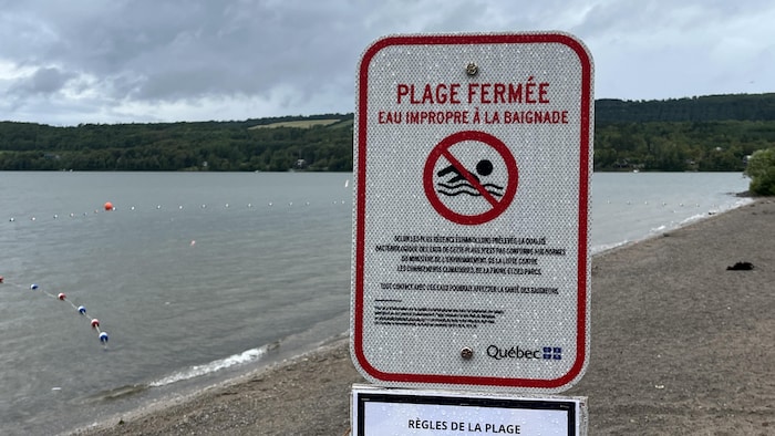 Une affiche indiquant que l'eau du lac est impropre à la baignade et que la plage est fermée.