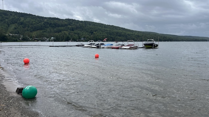 Des bateaux amarrés à un quai flottant sur un lac entouré de montagnes.