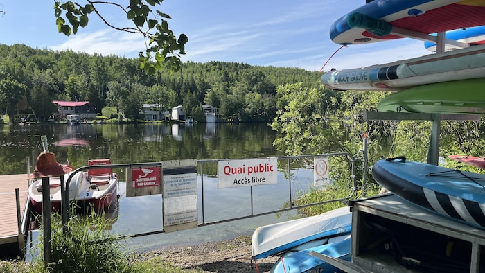 Un quai, un pédalo, une plage et des embarcations sur le bord d'un lac.