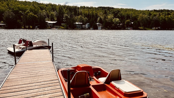 Un quai s'avance dans un lac. Des pédalos y sont attachés. 