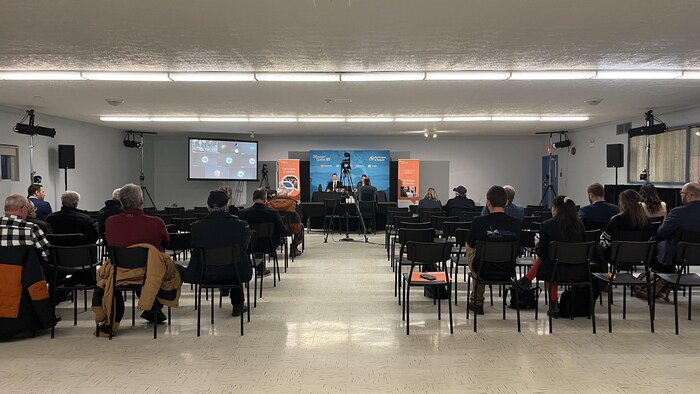 Une salle dans laquelle sont assises 25 personnes devant deux commissaires du BAPE. 