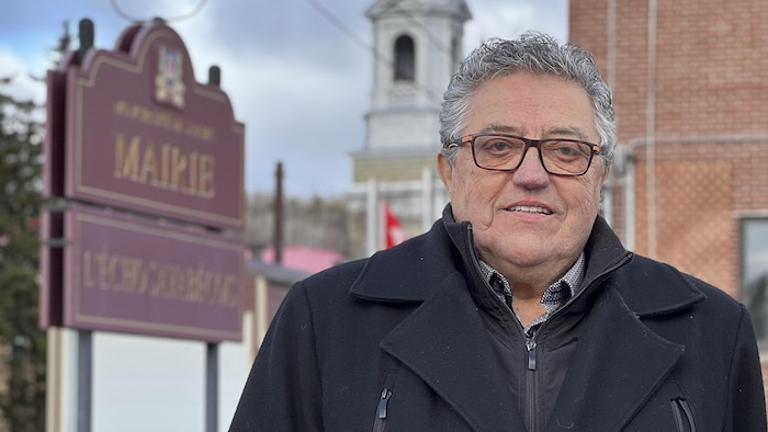L'élu est devant une affiche municipale.