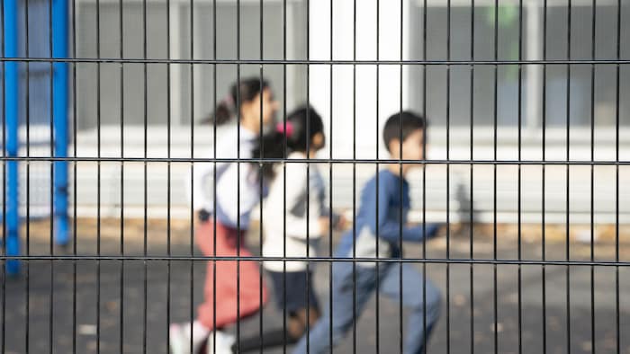 Un garçon et deux fillettes courent par une journée ensoleillée dans la cour d'une école.