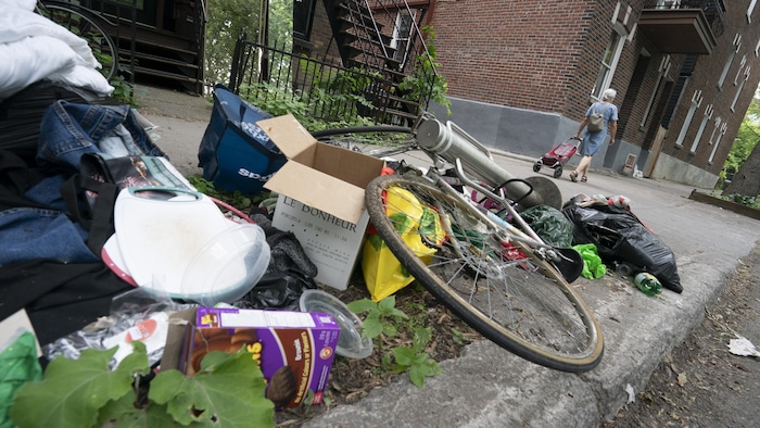 Un vieux vélo et de nombreux déchets jonchent le sol.