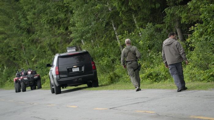 Des policiers effectuent des recherches en bordure de route.