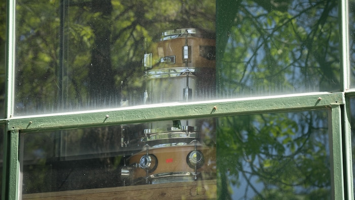 Des caisses de batterie empilées derrière la fenêtre d'un studio de pratique.