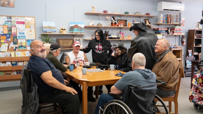 Des gens discutent autour d'une table au café communautaire la Place publique.