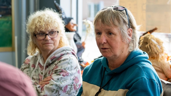 Line Perron est assise à la Place publique. Elle est en train de raconter quelque chose.