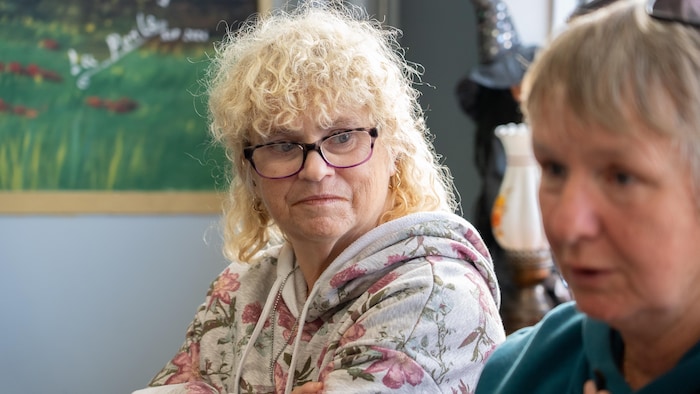 Martine Morneau est assise à la Place publique. Elle regarde Line Perron.