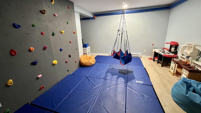 Un salon avec un mur d'escalade et des tapis d'exercice.