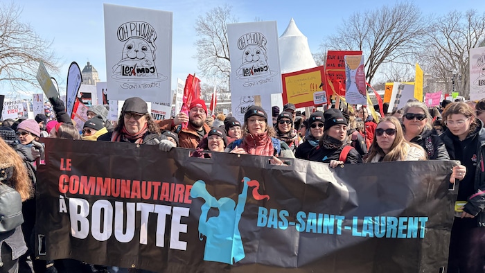 Un groupe de manifestants portant une bannière du mouvement Le communautaire à boutte. 