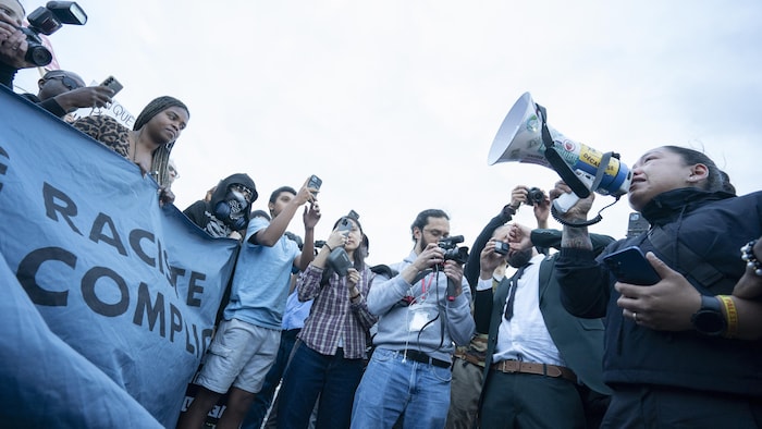 Une personne prend la parole devant des manifestants. 