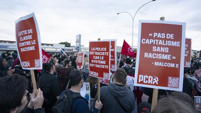 Des gens tiennent des pancartes sur lesquelles il est écrit "Pas de capitalisme sans racisme". 