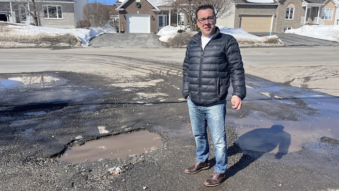 Mario Aubé devant un nid-de-poule.