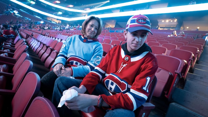 Un jeune homme et sa mère dans les gradins du Centre Bell.