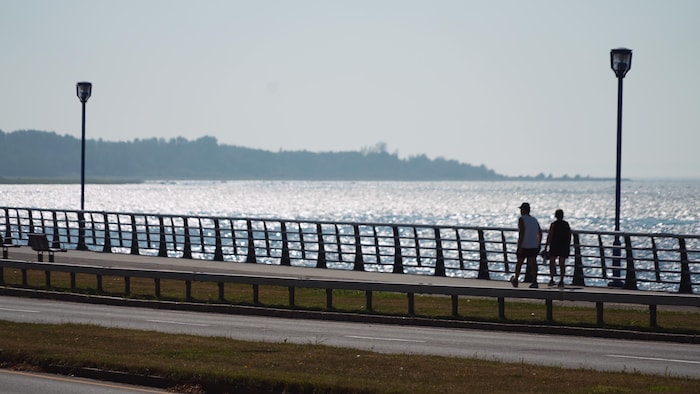 Deux personnes marchent sur le bord du fleuve à Rimouski.