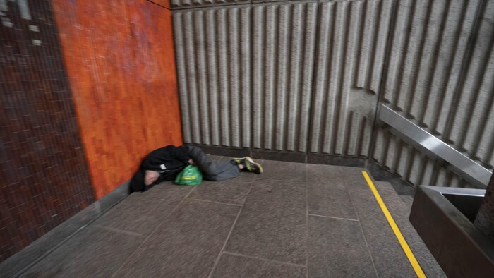 Une personne couchée dans un métro de Montréal.