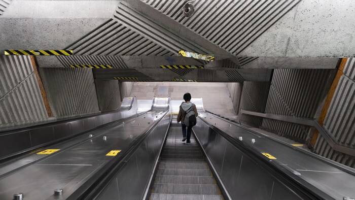 Un usager descend les escaliers dans le métro.