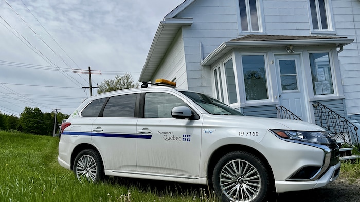 Une voiture du ministère des Transports du Québec stationnée devant une maison.