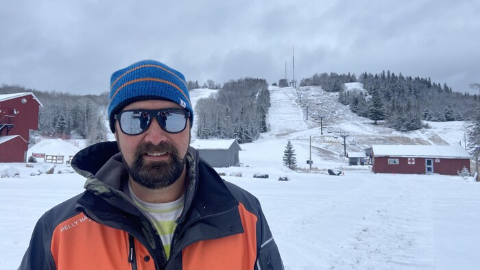 Daniel Kardas avec une tuque devant une pente de ski