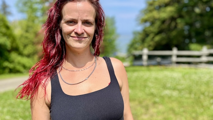 Myrianne Brisson-Ferlatte sourit à la caméra en faisant dos au fleuve Saint-Laurent.