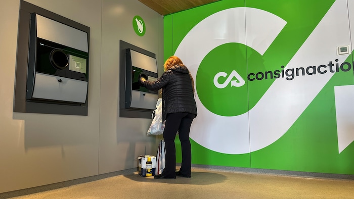 Une femme dépose des canettes et des bouteilles dans un appareil de récupération.