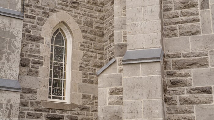 Un vitrail et une paroi d'une église en pierre.