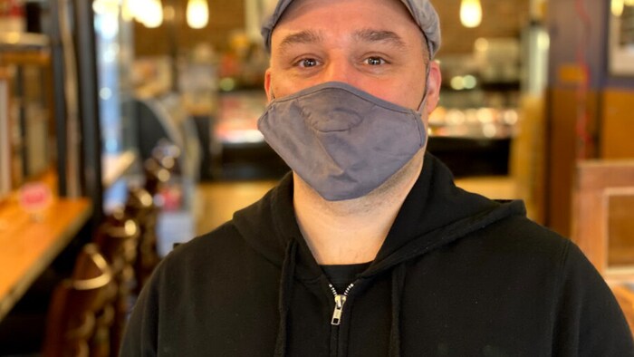 Patrick Reynard porte un masque gris et une casquette dans un restaurant.