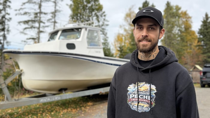 Un homme devant son bateau.