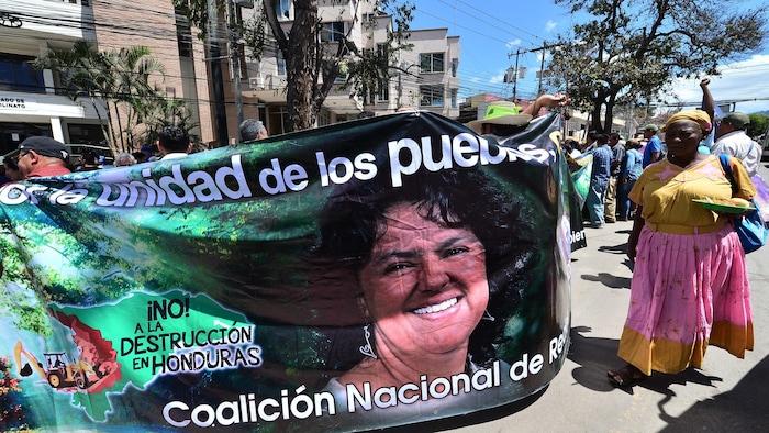 Manifestants pour la libération de 13 écologistes avec une banderole représentant la leader écologiste assassinée hondurienne Berta Caceres alors qu'ils arrivent à une audience à Tegucigalpa le 28 février 2019. Les treize leaders écologistes de la communauté de Guapinol, qui s'opposent à l'exploitation minière du parc national en Montana de Botaderos par l'entreprise Inversiones Los Pinares, ont été arrêtés pour usurpation, incendie, vol aggravé et association illicite. 