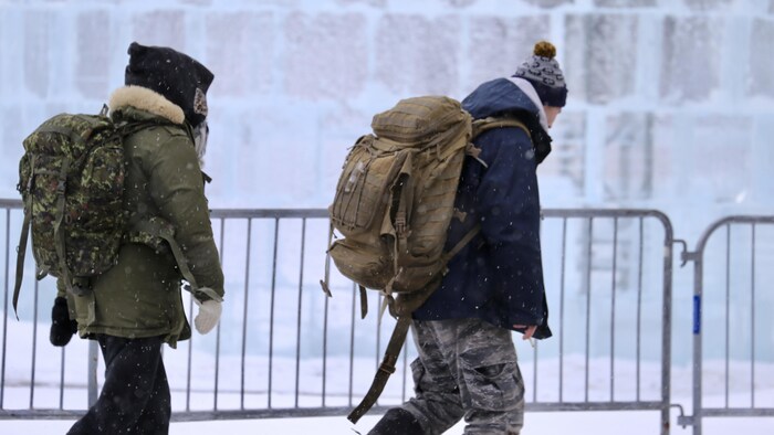 Deux personnes marchent dans le Vieux-Québec avec un sac sur le dos.