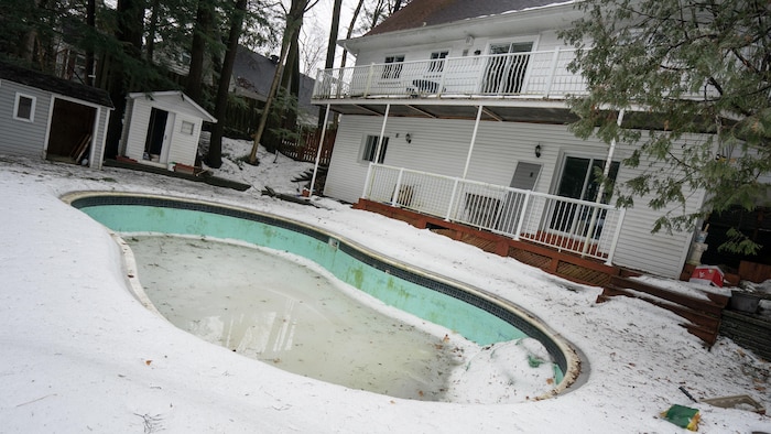 A swimming pool at the back of a house in winter. 