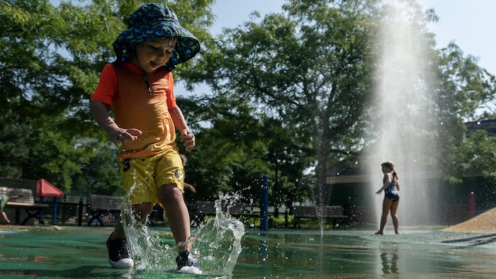 Un enfant se rafraîchit dans un jeu d'eau.