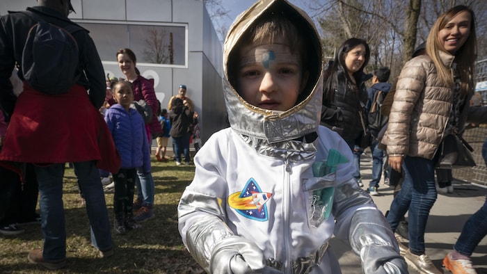Un jeune garçon qui porte un costume d'astronaute dans un parc.