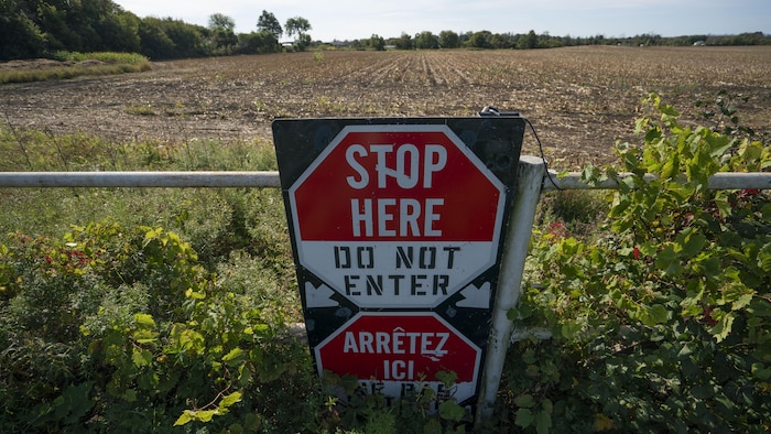 Une affiche posée sur une clôture dans un champ.